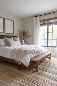 a large bed sitting in a bedroom next to a window with two framed pictures on the wall