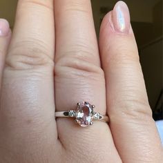 a woman's hand with a ring on it and a pink diamond in the middle