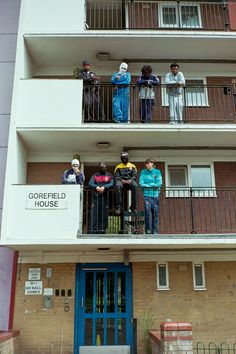 several people are standing on the balconies of an apartment building