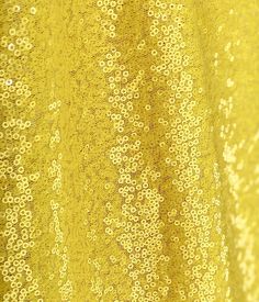 yellow sequin fabric with small white flowers on the top and bottom, close up