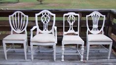 four white chairs sitting on top of a wooden deck