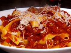 a white bowl filled with pasta covered in sauce and parmesan cheese on top