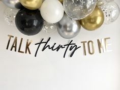 balloons and confetti are arranged on the wall for a talk thirty - one party