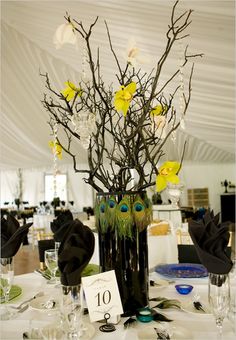 the centerpiece is decorated with yellow flowers and branches, which are adorned with feathers