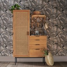 a wooden cabinet sitting on top of a hard wood floor next to a wall covered in plants