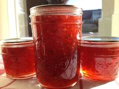 three jars filled with red liquid sitting on top of a table