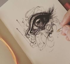 a person's hand is holding a pencil and drawing an eye