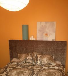 a bedroom with an orange wall and brown headboard on the bed is pictured in this image