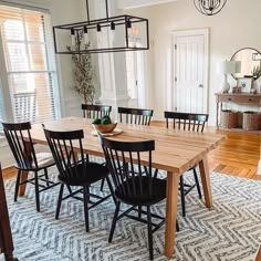 a dining room table with black chairs and an area rug