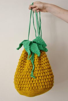 a crocheted bag hanging from a hook in someone's hand with a green handle