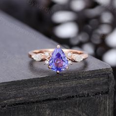 a tan gold ring with an amethorate and diamond accented band, sitting on top of a wooden table