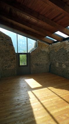 an empty room with stone walls and wooden floors is shown in this image, the sun shines through the windows