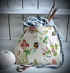 a purse with yarn and knitting needles in it next to a ball of yarn on a table