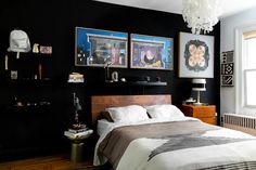 a bedroom with black walls and pictures on the wall above the bed, along with other decor items