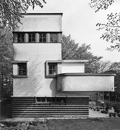 a black and white photo of a house with stairs leading up to the front door