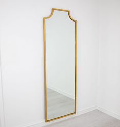 a large mirror sitting on top of a white wall next to a wooden flooring