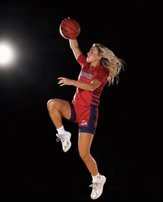 a female basketball player jumping in the air with a ball