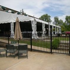 an outdoor area with tables and chairs, umbrellas and gazebo in the background