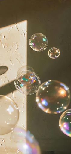 soap bubbles floating in the air next to a white wall and window with sunlight coming through it