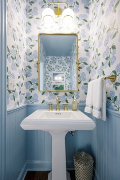 a white sink sitting under a mirror in a bathroom next to a wall mounted light