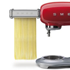 a red pasta maker with spaghetti in front of it