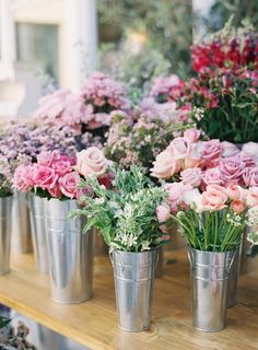 several metal buckets filled with pink and white flowers