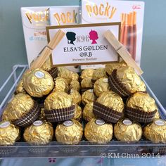 a display case filled with chocolate covered candies and wrapped in gold foil wrappers