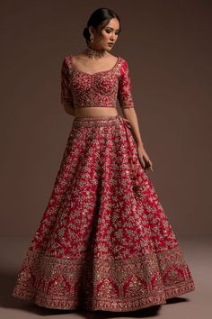 a woman in a red and gold lehenga with matching crop top, skirt and dupatta