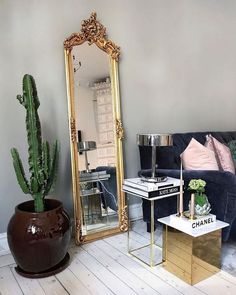 a living room filled with furniture and a large mirror on top of a wooden floor