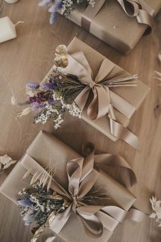 three wrapped presents sitting on top of a wooden table next to candles and vases