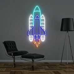 a wall mounted neon sign with a rocket ship on the side and a black chair next to it