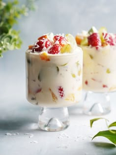 two desserts with fruit on top and flowers in the background, sitting next to each other