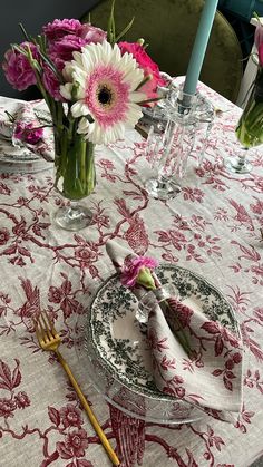 a table topped with plates and vases filled with flowers