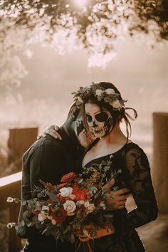 a man and woman dressed up as skeletons hugging each other with flowers in their hair