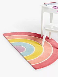 a small white chair sitting on top of a rug next to a table with a book