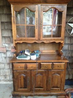 an old wooden china cabinet with glass doors