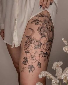 a woman's thigh with flowers and koi fish tattoo on her leg, next to white flowers