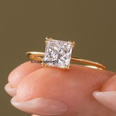 a close up of a person holding a ring with a princess cut diamond in it