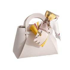 a white purse with a yellow bow on the front and bottom handle, sitting on a white surface