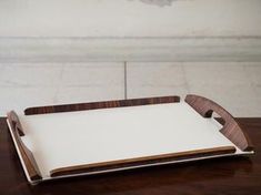 a wooden serving tray with white paper on top and brown trim around the edge, sitting on a wood table