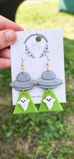 a pair of green and white earrings with a ghost on it