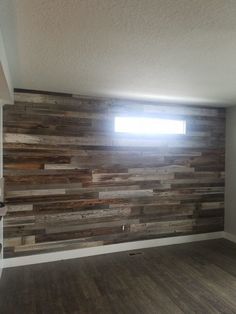 an empty room with wood planks on the wall and a window in the corner