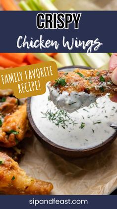 a person dipping chicken wings into a bowl with ranch dressing on it and carrots in the background