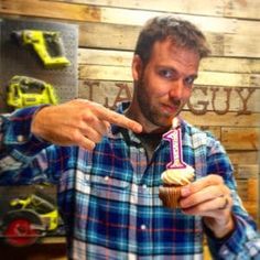 a man pointing at a cupcake with the number one on it