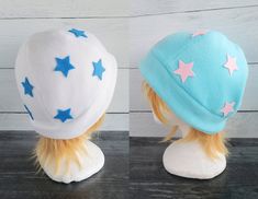 two hats with blue and pink stars on them sitting on top of a wooden table