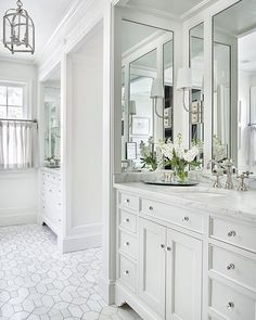 a white bathroom with double sinks and mirrors