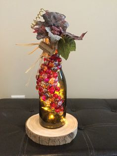 a glass vase filled with lots of different colored beads and flowers on top of a table