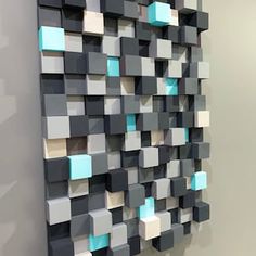 a wall sculpture made out of squares and rectangles in grey, white, and blue