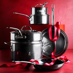 several pots and pans with red ribbon around them on a red tableclothed surface