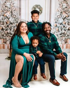 a family poses in front of christmas trees